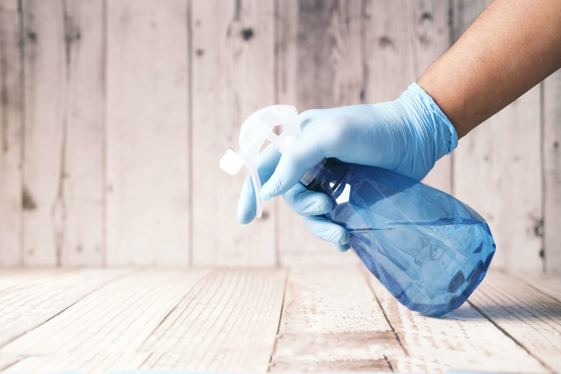 Hand holding a household cleaning spray bottle